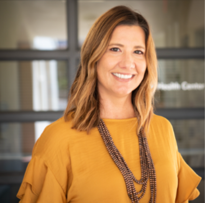 A woman with light brown hair smiling.