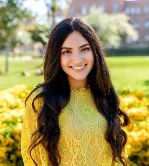 A young woman with long dark hair smiles widely