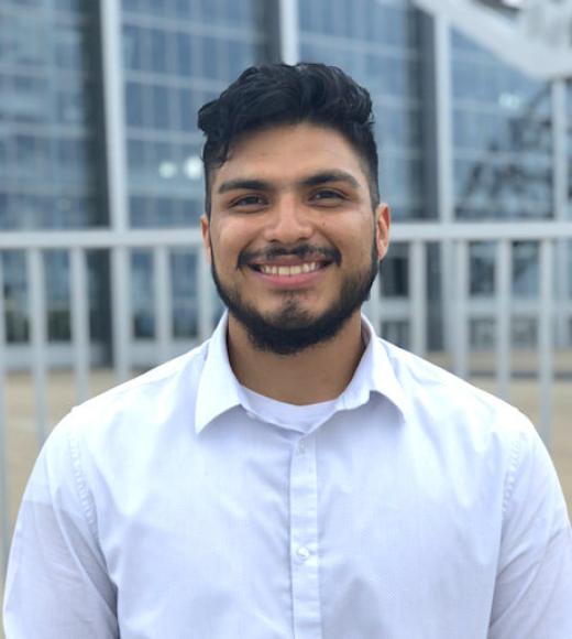 A young man with black hair and beard smiles