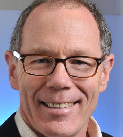 Headshot of a man of middle age with glasses, shirt and suit jacket