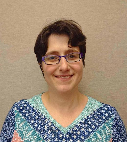 A woman with short hair, glasses and patterned shirt.