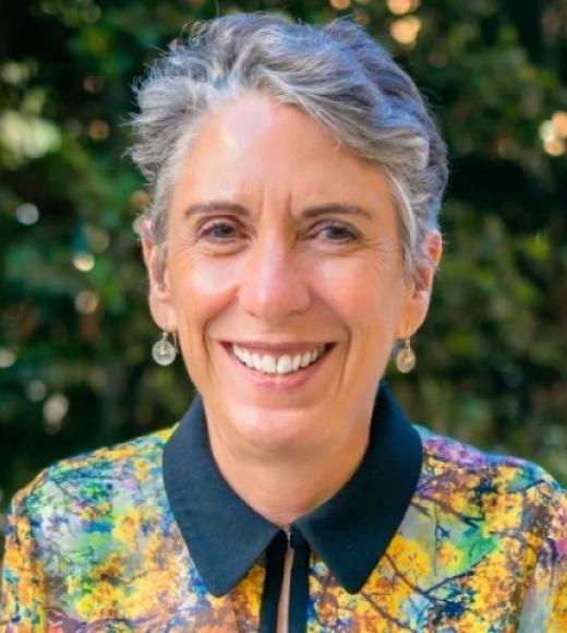 A woman with cropped gray hair and a colorful blouse.