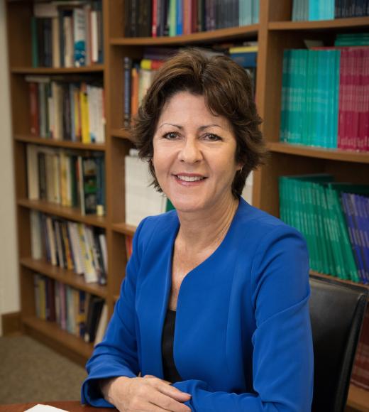 A woman with short brown hair smiles in a university office.