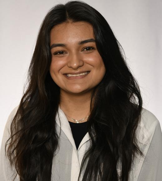 A young woman with long dark hair smiles.