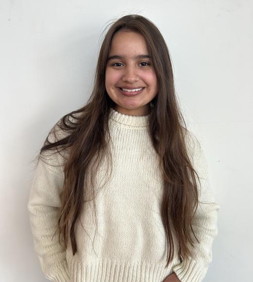 A young woman with long brown hair smiles widely