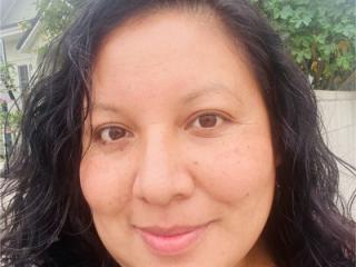 A woman with dark curly hair smiles warmly.