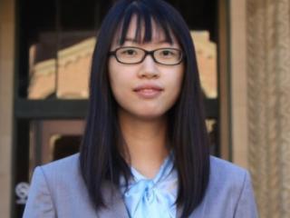 A young person with straight black hair, glasses, and semiformal attire.