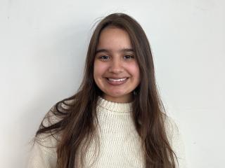 A young woman with long brown hair smiles widely